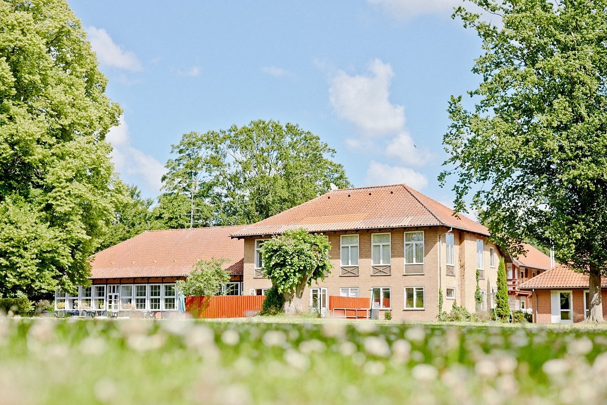 Vesterskoven — a pale yellow manor house surrounded by tall trees and a summer garden